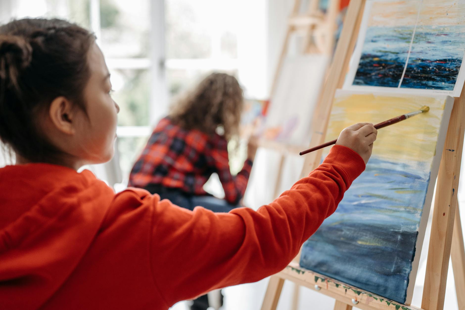 Children painting on easels in a vibrant classroom