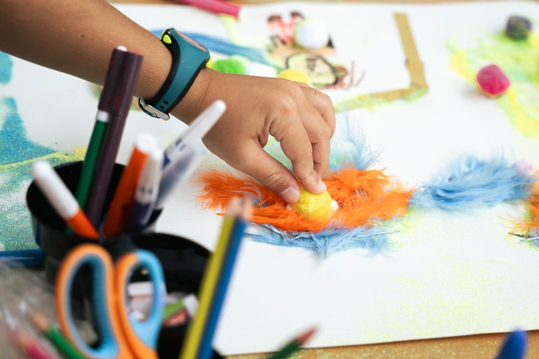 Child creating art with colorful feathers and markers