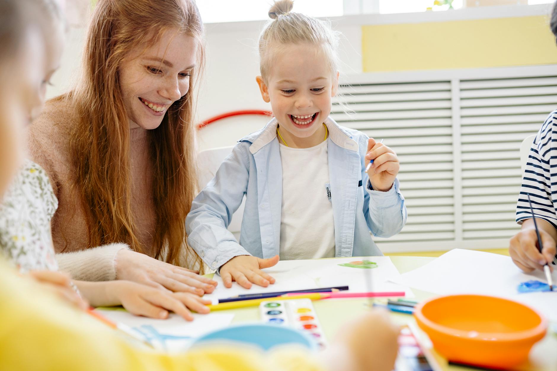 Happy children and teacher enjoying a creative arts and crafts session in a classroom