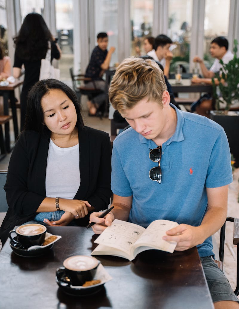 An educator and a teenager working through a workbook together at a table, one on one.