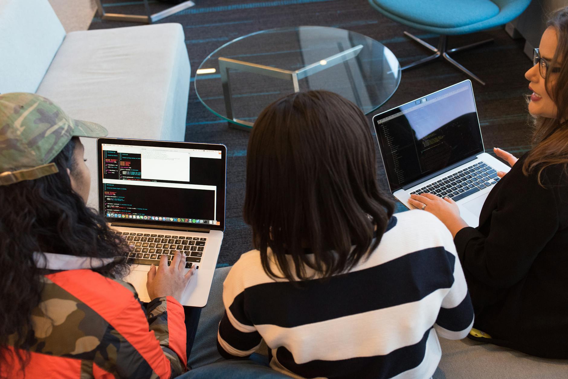 Three women working on laptops in a stylish office, collaborative coding