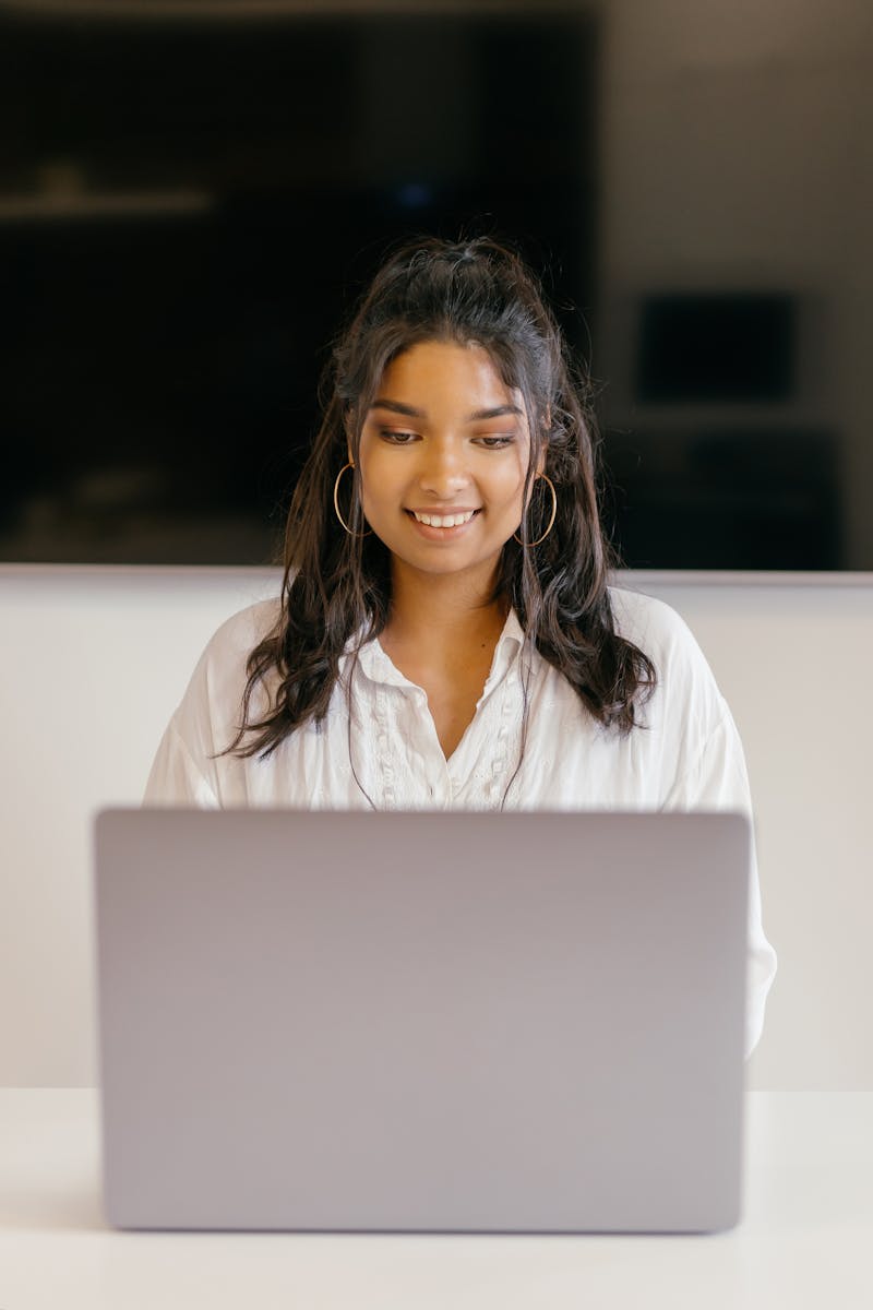 Female student smiling while using a laptop for college prep