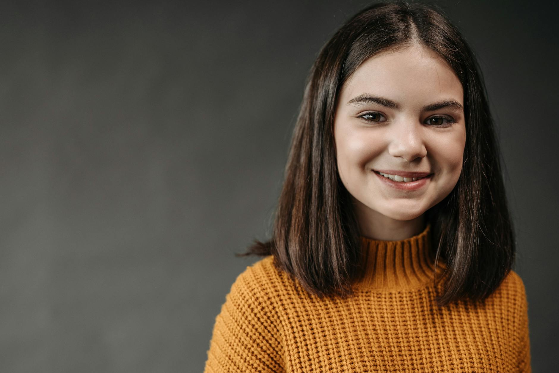 Smiling young woman in cozy orange sweater, the confidence Plato+ students gain