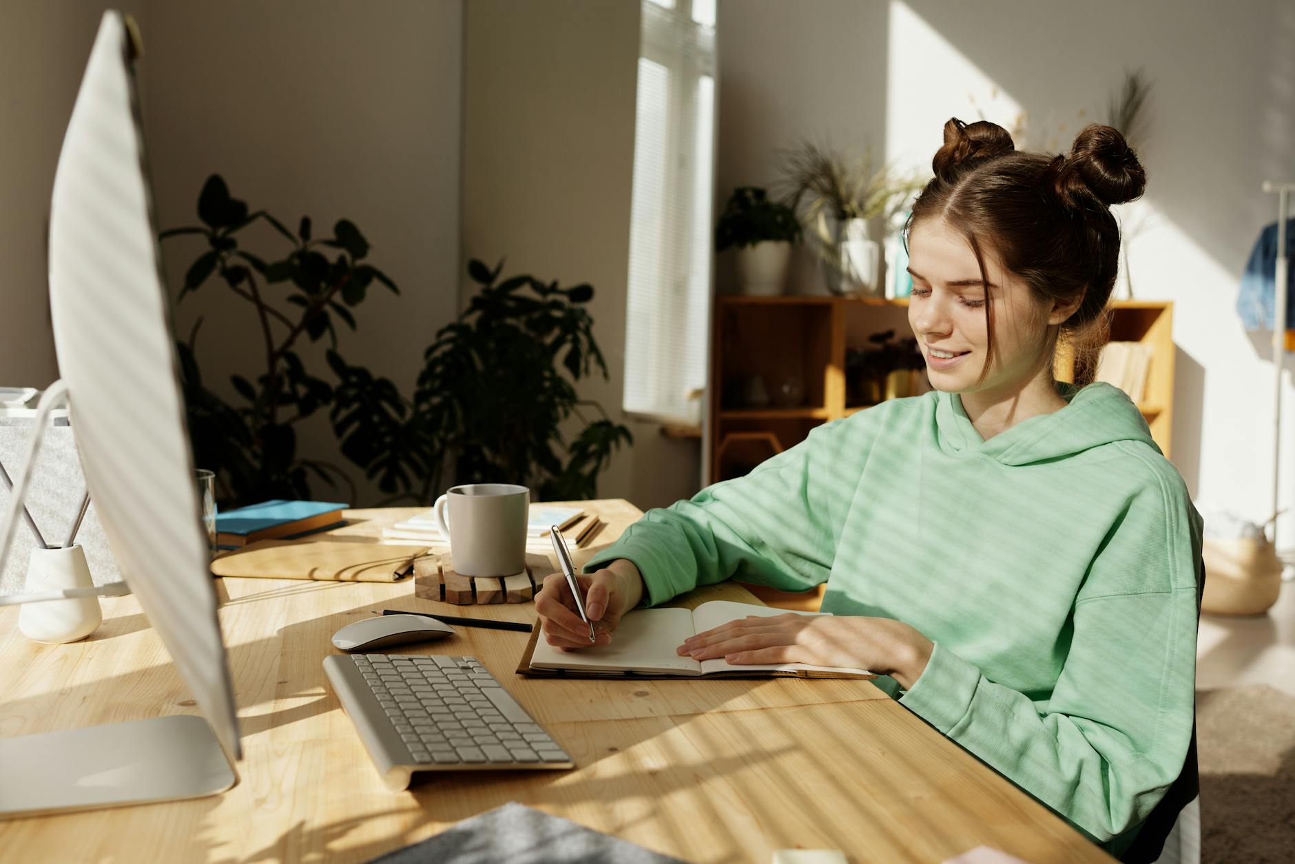Teen girl studying at a desk, writing in a notebook illuminated by sunlight. Focused test preparation