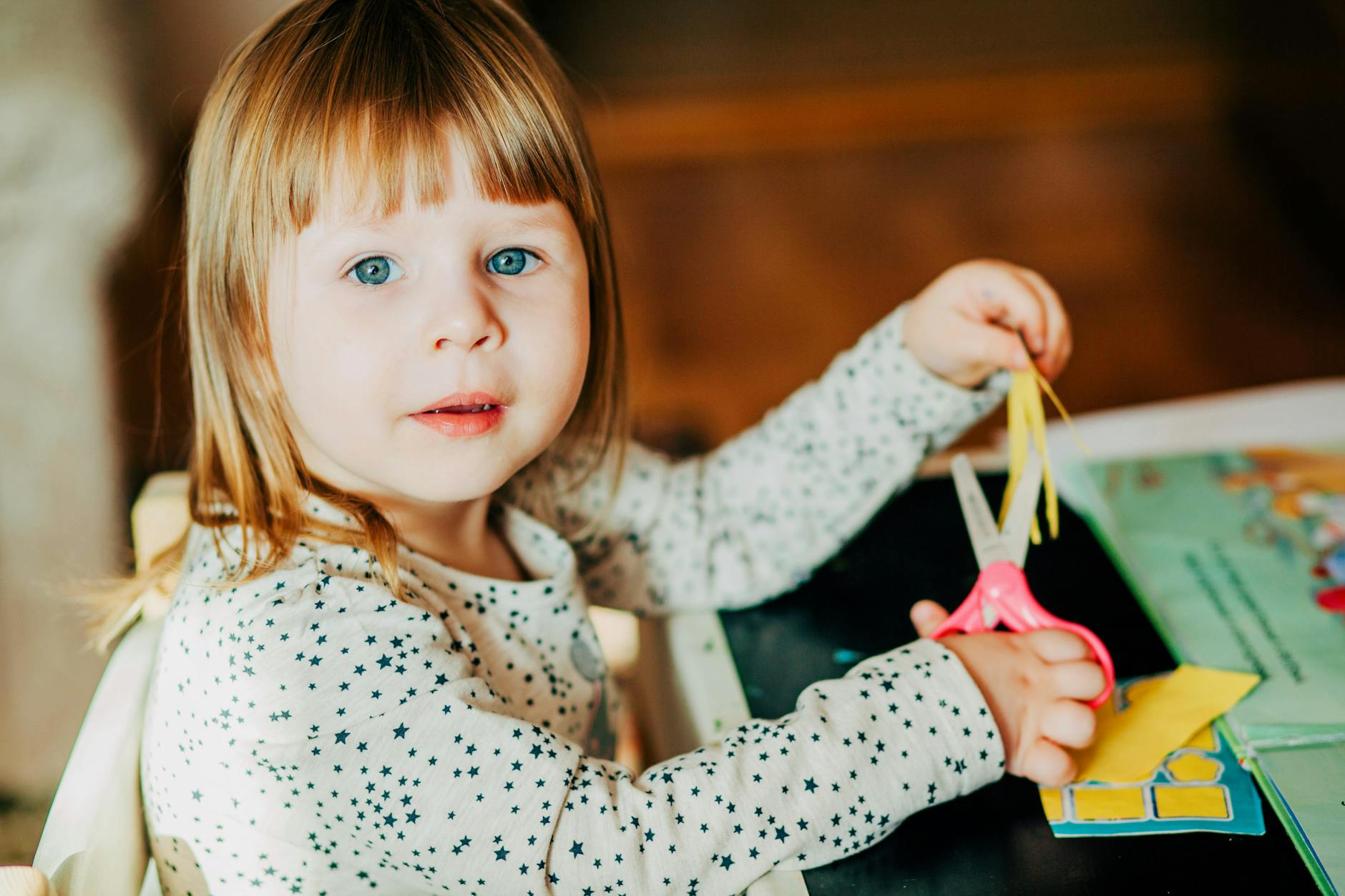 Young girl using scissors for arts and crafts in a cozy indoor setting