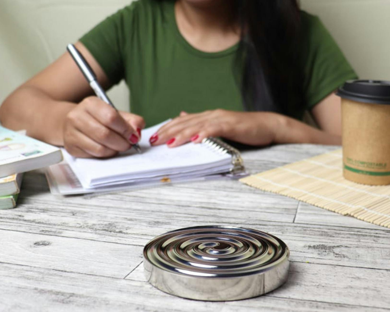 Woman writing in a notebook at a desk with coffee. Productive study session